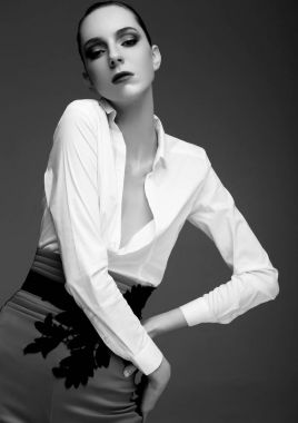 Gri pantolon ve beyaz gömlek giymiş bir modeldir