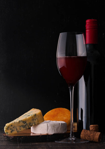 Bottle and glass of red wine with cheese selection