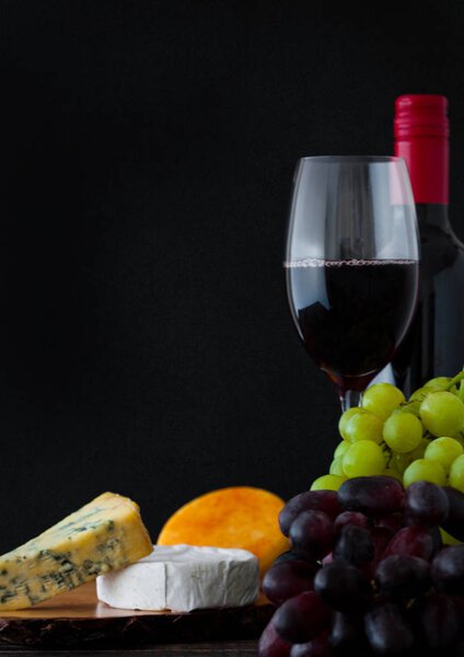 Bottle and glass of red wine with cheese selection