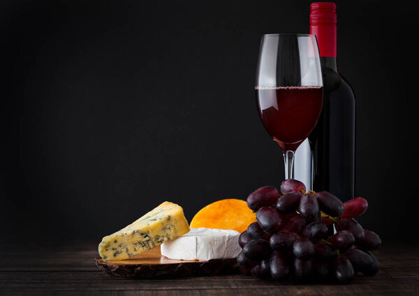 Bottle and glass of red wine with cheese selection