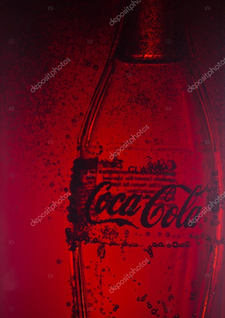 LONDON, UK - JANUARY 02, 2018: Cold glass bottle of Coca Cola drink inside cola glass container with bubbles. The drink is produced and manufactured by The Coca-Cola Company.