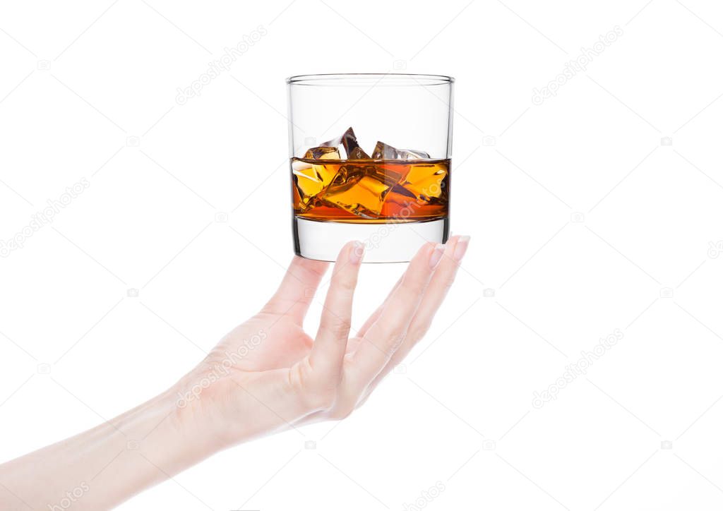 Female hand holding whiskey glass with ice