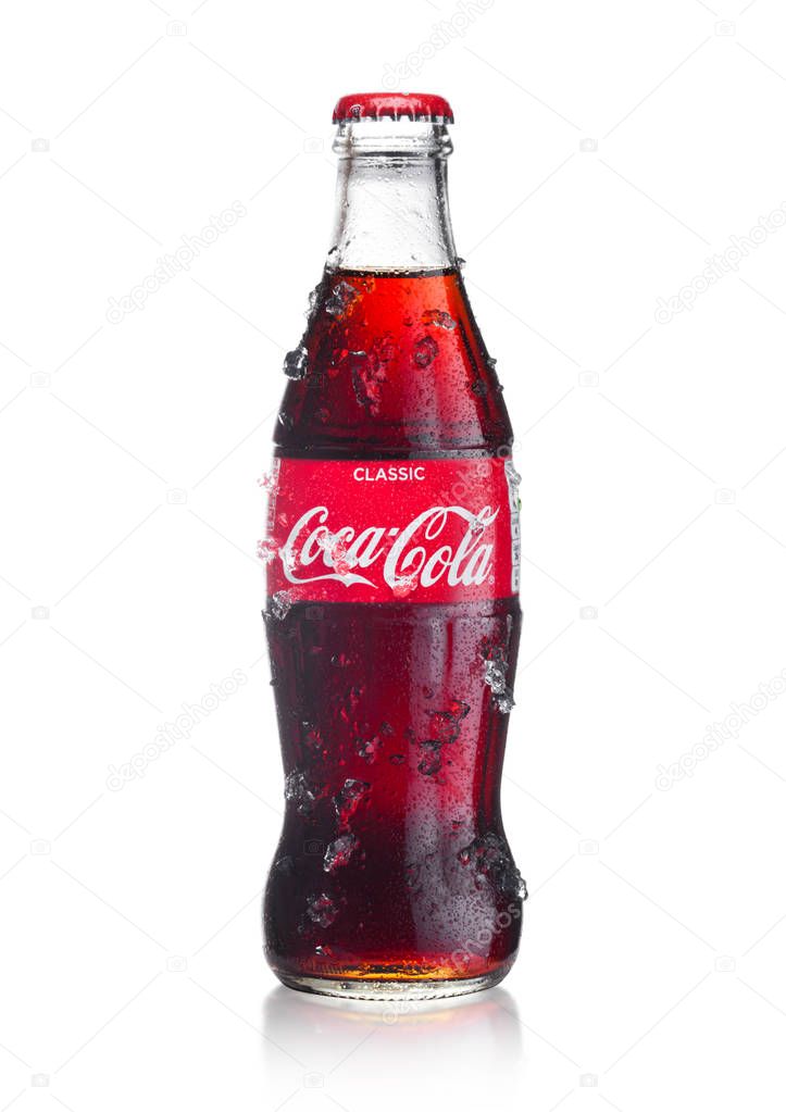 LONDON, UK - JANUARY 20, 2018: Cold glass bottle of Coca Cola drink  with ice and dew on white background. The drink is produced and manufactured by The Coca-Cola Company.