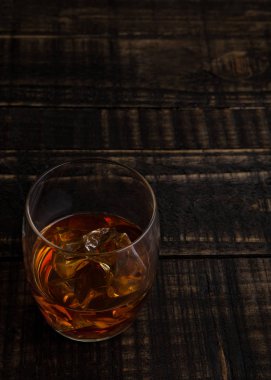 Tahta masada buz küpleri olan bir bardak viski.