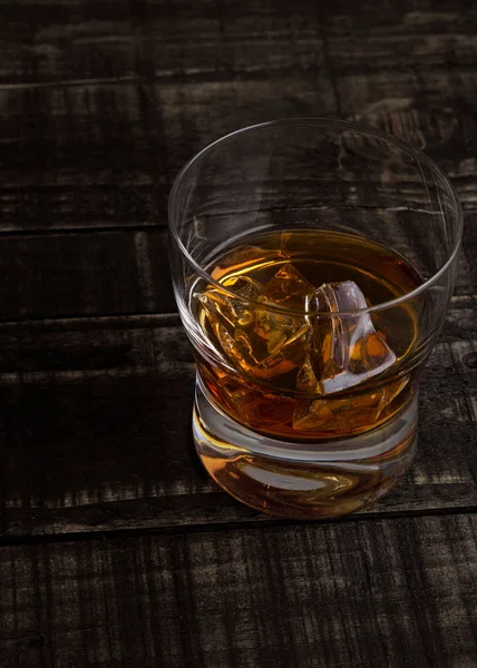 Glas Whisky mit Eiswürfeln auf Holztisch — Stockfoto