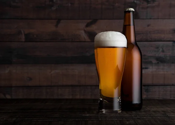 Glass and bottle of golden lager beer with foam — Stock Photo, Image