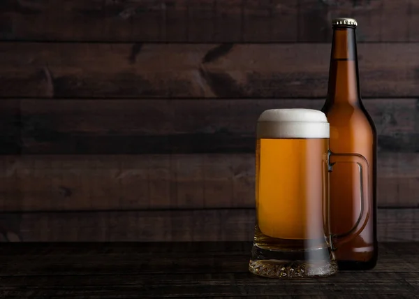 Glass and bottle of golden lager beer with foam — Stock Photo, Image