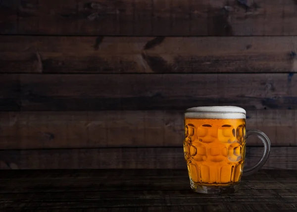 Glass of golden lager ale beer with foam on wood — Stock Photo, Image