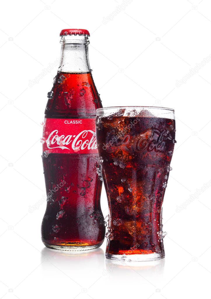 LONDON, UK - FEBRUARY 02, 2018: Cold bottle and glass of Classic Coca Cola  drink on white background with ice and dew. The drink is produced and manufactured by The Coca-Cola Company.