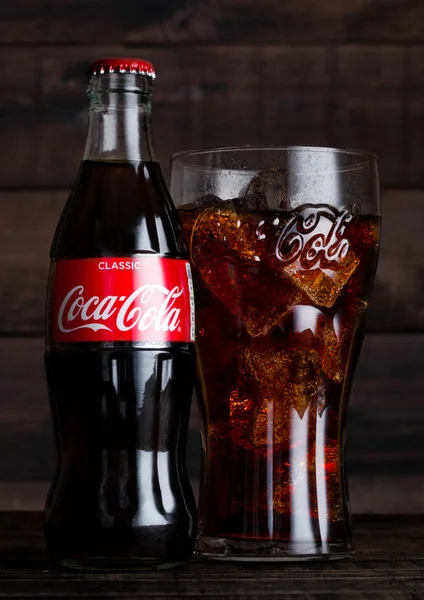 ЛОНДОН, Великобритания - 14 февраля 2018 года: Оригинальный стакан и бутылка напитка Coca Cola со льдом на дереве. Напиток производится и производится компанией The Coca-Cola Company . — стоковое фото