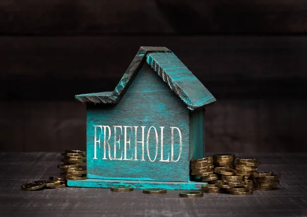 Dřevěný dům model s mincí vedle ní a rukou — Stock fotografie