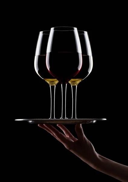 Hand with glove holds tray with glasses of wine