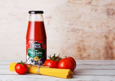 Londra, İngiltere - 10 Mart 2018: Cam şişe Cook Italia Passata sos spagetti ve ahşap üzerine çiğ domates ile.