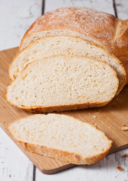 Frisch gebackener Brotlaib mit Stücken auf Holzbrett — Stockfoto