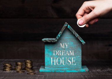 Ahşap ev modeli sikke yanındaki o ve el ile