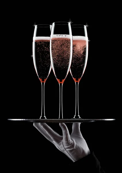 Hand with glove holds tray with champagne glasses