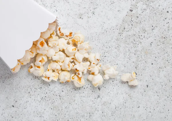 Papiercontainer mit frisch gesalzenem Popcorn auf Stein — Stockfoto