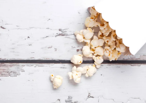 Paper container with fresh salted popcorn on wood — Stock Photo, Image
