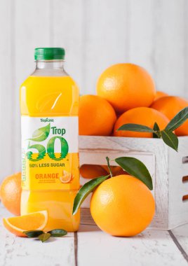 LONDON, UK - MARCH 31, 2018: Plastic bottle of fresh Tropicana Tropical Orange Juice with fresh raw oranges on white wood. clipart