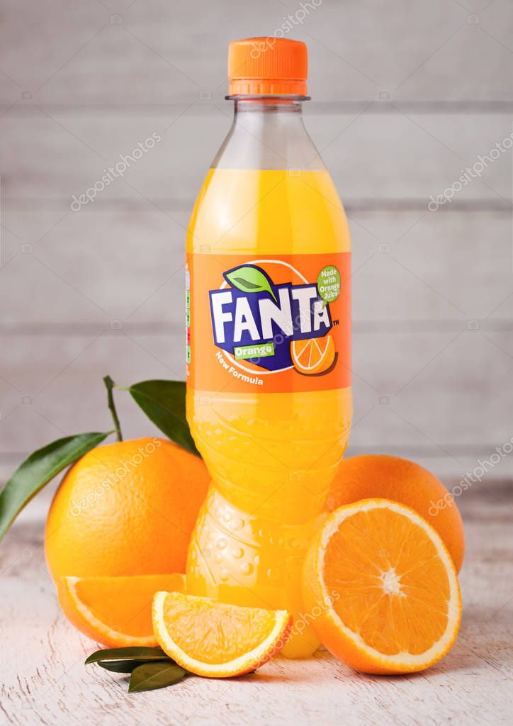 LONDON, UK - MARCH 31, 2018: Plastic bottle of Fanta orange soft drink on light wooden background with fresh raw oranges.