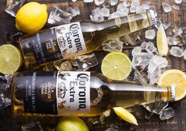 Londra, İngiltere - 27 Nisan 2018: Cam şişeler, Corona ilave bira buz küpleri ve taze limon ile ahşap arka plan üzerinde. Üstten Görünüm
