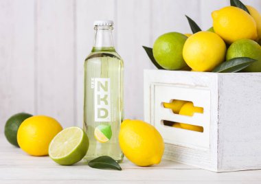 Londra, İngiltere - 27 Nisan 2018: Nkd alkollü kokteyl içki taze limon ve limes ahşap zemin üzerine cam şişe.