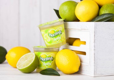 Londra, İngiltere - 27 Nisan 2018: Plastik bardak taze limon ve limes ahşap arka plan Hartley'in jöle.