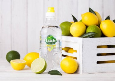 Londra, İngiltere - 12 Nisan 2017: Plastik şişe limon ve limes ahşap zemin üzerine Volvic durgun su. 