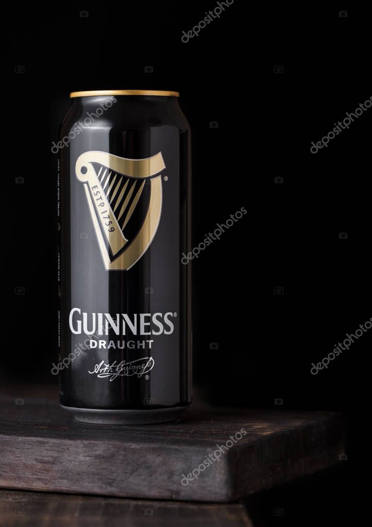 LONDON, UK - APRIL 27, 2018: Aluminium cans of Guinness draught stout beer bottle on dark wooden background. Guinness beer has been produced since 1759 in Dublin, Ireland.