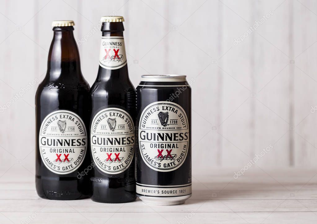 LONDON, UK - APRIL 27, 2018: Bottles and aluminium can of Guinness extra stout beer  bottle on light wooden background. Guinness beer has been produced since 1759 in Dublin, Ireland.