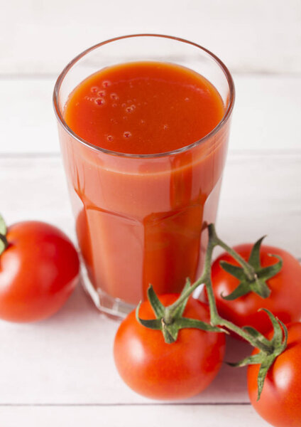 Glass of tomato juice with fresh raw tomatoes