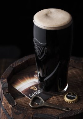 Londra, İngiltere - 03 Mayıs 2018: Orijinal bardak Guinness fıçı şişman bira şişe açacağı ile ahşap varil üzerine.