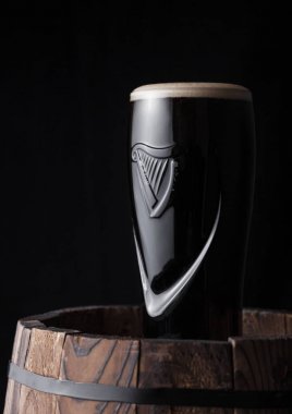 Londra, İngiltere - 03 Mayıs 2018: Orijinal bardak Guinness fıçı şişman bira koyu ahşap arka plan üzerinde ahşap varil üzerine.