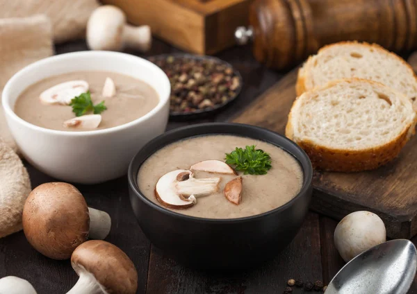 Ceramic bowl plates of creamy chestnut champignon mushroom soup with spoon, pepper and kitchen cloth on dark wooden background and fresh bread. — Stock Image Ceramic bowl plates of creamy chestnut champignon mushroom soup with spoon, pepper and kitchen cloth on dark wooden background and fresh bread. Royalty Free Stock Photos