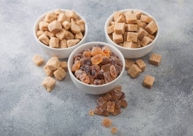 Beyaz seramik tabaklar, rafine edilmemiş doğal kahverengi tabaklar ve arka planda karamelize şeker küpleri..