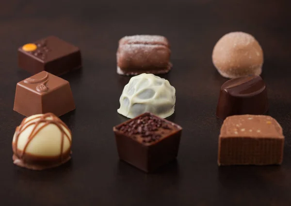 Selección de caramelos de chocolate de lujo sobre fondo de mesa marrón. Surtido de chocolate blanco, oscuro y leche . — Foto de Stock