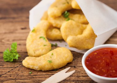 Ahşap arka plan üzerinde ahşap çatal ve ketçap ile kağıt torba içinde tereyağlı tavuk nuggets.