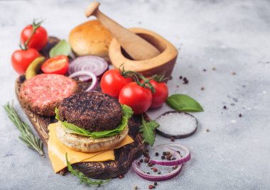 Taze çiğ kıyma ve ızgara biber sığır eti burger ahşap arka plan üzerinde çörekler soğan ve domates ile vintage doğrama tahtası üzerinde. Turşu ve fesleğen ile havaneli harç.