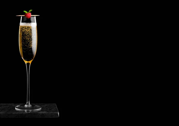 Copo elegante de champanhe amarelo com rasspbery no pau em placa de mármore preto no fundo preto. Espaço para texto — Fotografia de Stock