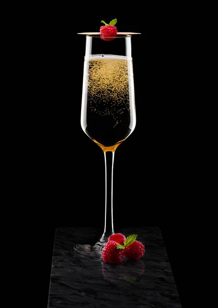 Elegante copa de champán amarillo con rasspbery y bayas frescas con hoja de menta en palo sobre tablero de mármol negro sobre fondo negro . —  Fotos de Stock