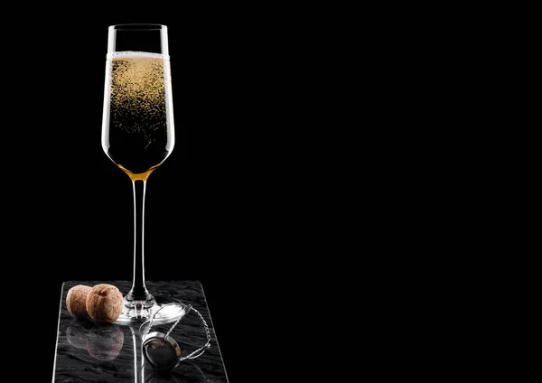 Elegant glas gul champagne med kork och tråd bur på svart marmor ombord på svart bakgrund. Plats för text — Stockfoto