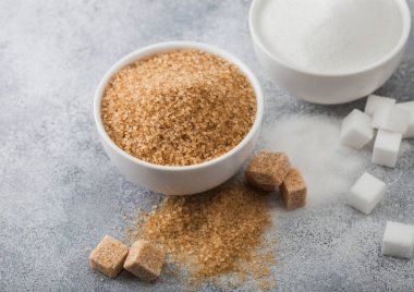 Beyaz kase tabakları, açık masa zemininde doğal kahverengi ve beyaz rafine şeker ve küp..