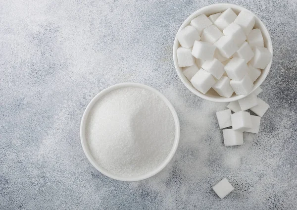 Piatti ciotola bianca di cubetti di zucchero bianco naturale e zucchero raffinato su sfondo tavolo leggero . — Foto Stock