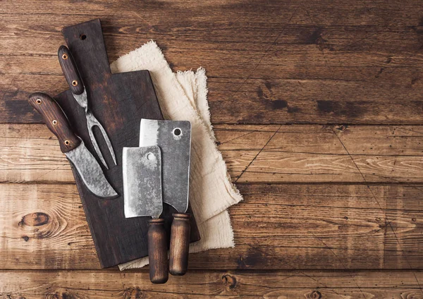 Escotillas vintage para carne sobre tabla de cortar de madera sobre fondo de mesa de madera con toalla de lino y tenedor y cuchillo. Vista superior — Foto de Stock
