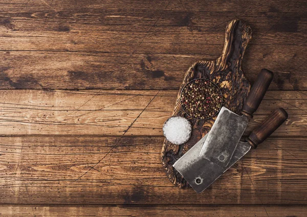 Klasyczne siekiery do mięsa na drewnianej desce do siekania z solą i pieprzem na drewnianym tle stołu. Miejsce na tekst — Zdjęcie stockowe