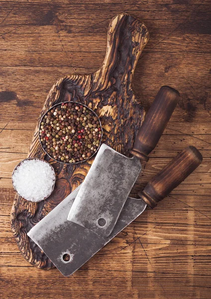 Escotillas vintage para carne sobre tabla de cortar de madera con sal y pimienta sobre fondo de mesa de madera . — Foto de Stock