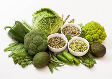 Beyaz arka plan üzerinde çeşitli yeşil tonda çiğ organik sebze. Avokado, lahana, brokoli, karnabahar ve salatalık kesilmiş ve mung fasulye, pak choi, gevşek biber ve marul ile. Tohumlu kase