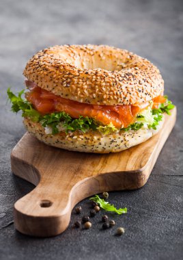 Taze sağlıklı simit sandviç, somon, ricotta ve marul. Mutfak arka planında eski usul doğrama tahtası. Sağlıklı diyet yemekleri. 
