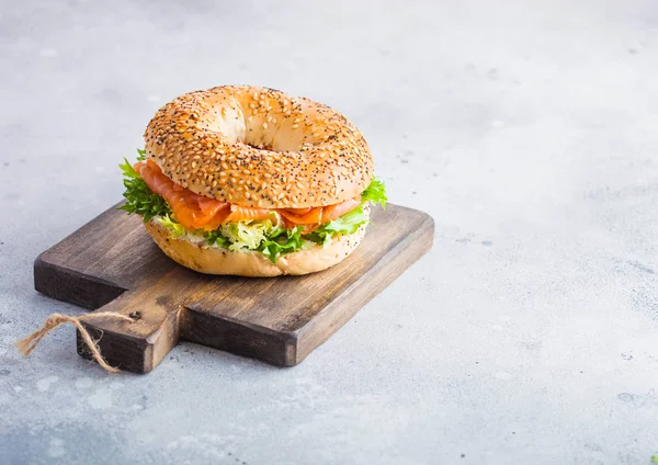 Sanduíche de bagel saudável fresco com salmão, ricota e alface na tábua de corte vintage em fundo de mesa de cozinha de pedra. Alimentação saudável. Espaço para texto — Fotografia de Stock