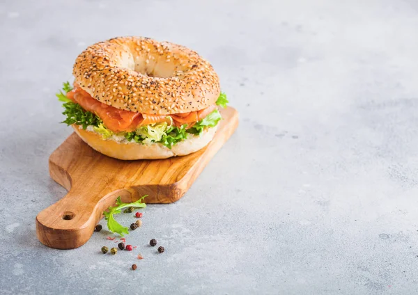 Sanduíche de bagel saudável fresco com salmão, ricota e alface na tábua de corte vintage no fundo da mesa da cozinha branca. Alimentação saudável. Pimenta de lado. Espaço para texto — Fotografia de Stock